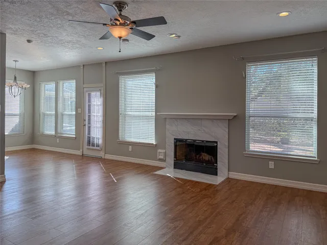 an empty room with wooden floor fireplace and windows