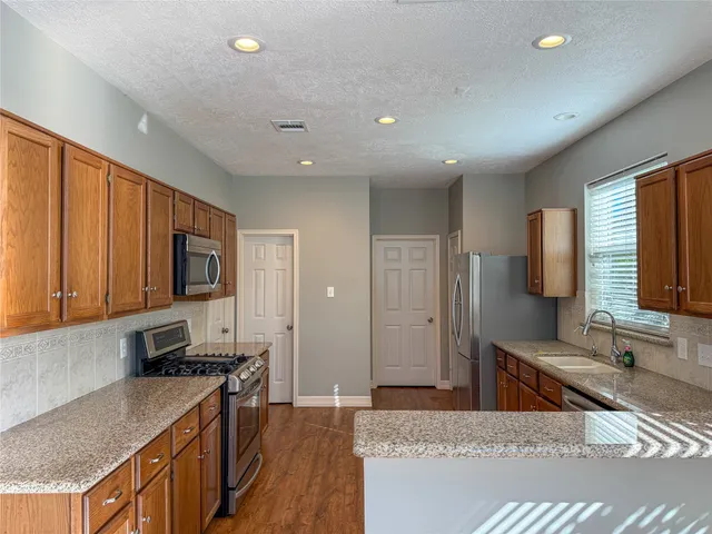 a kitchen with stainless steel appliances granite countertop a stove a sink and a refrigerator
