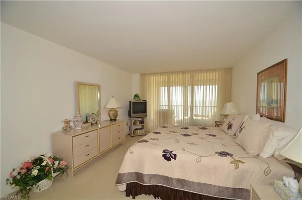 a bedroom with a bed a chandelier and dresser