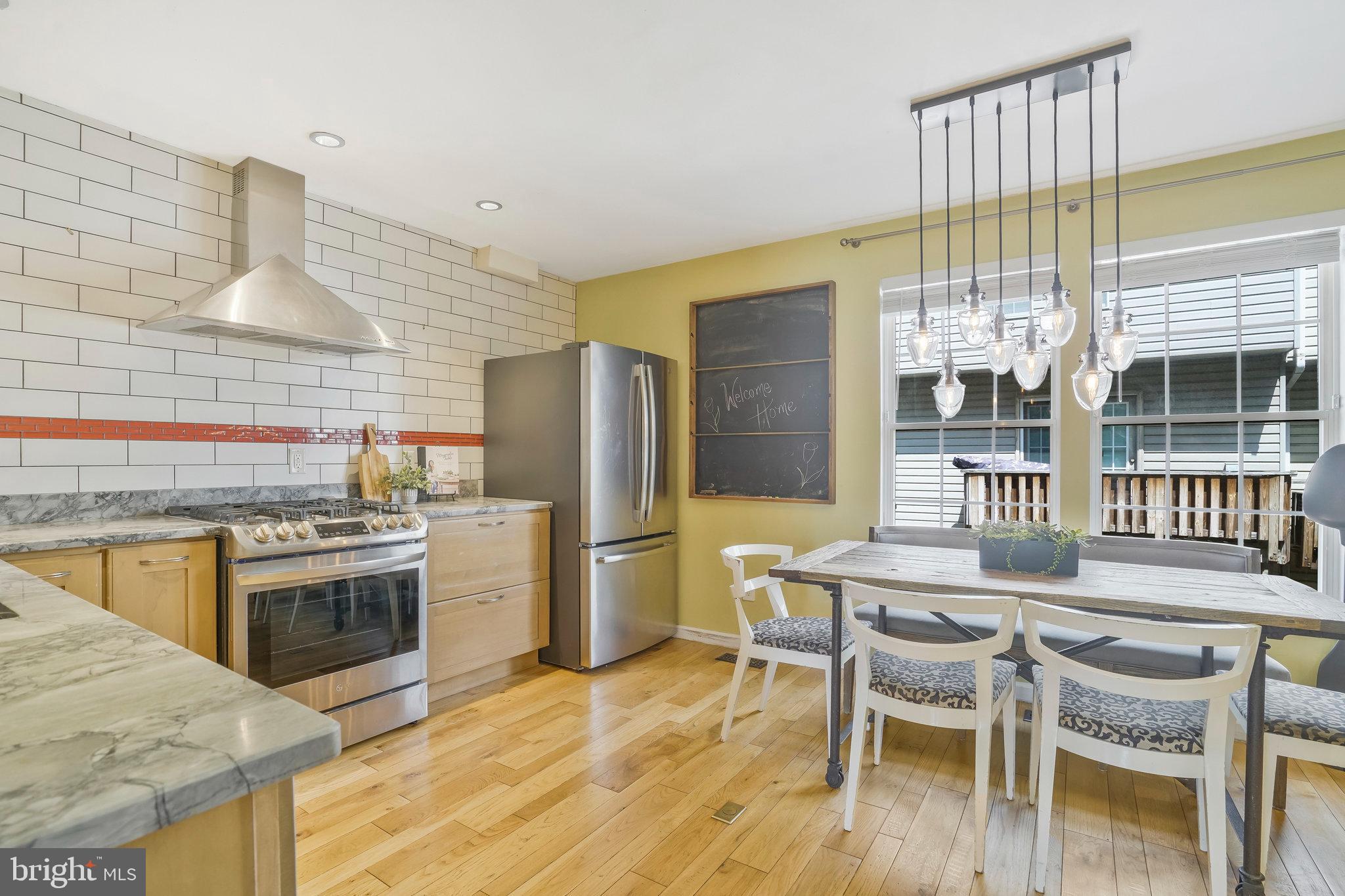 2181 Shirlington Road Arlington, VA 22206 - Photo 7 of 48 a kitchen with stainless steel appliances kitchen island a table chairs in it and wooden floors