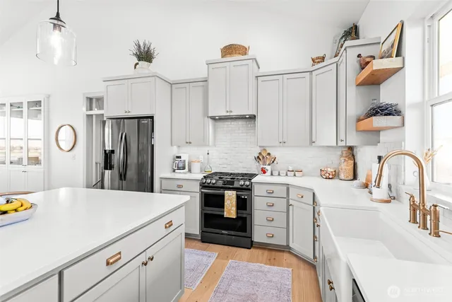 a kitchen with stainless steel appliances granite countertop a sink dishwasher a refrigerator and a stove with white cabinets