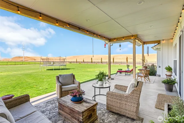 a view of a patio with couches potted plants and a big yard