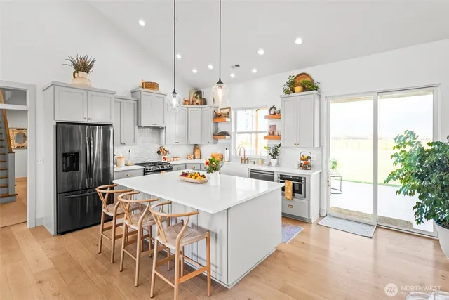 a kitchen that has a lot of white cabinets and stainless steel appliances