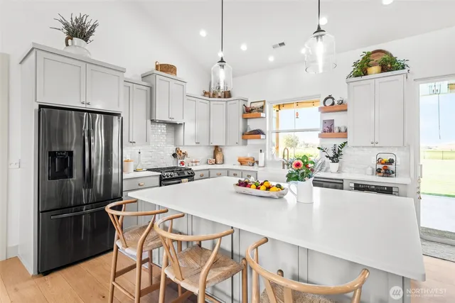 a kitchen with stainless steel appliances a refrigerator a sink dishwasher and white cabinets with wooden floor