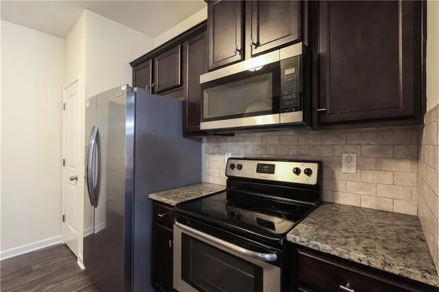 a kitchen with granite countertop cabinets stainless steel appliances and wooden floor