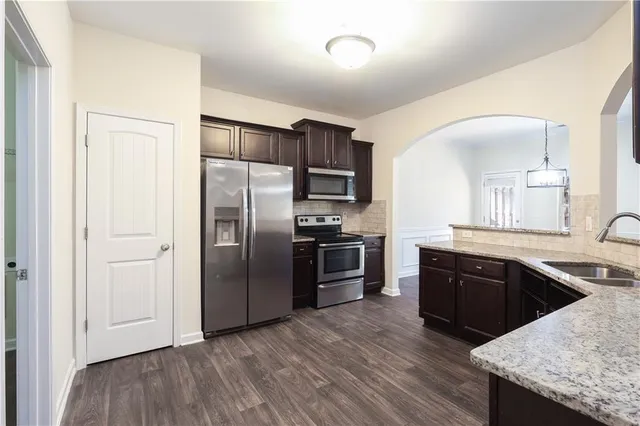 a kitchen with granite countertop a refrigerator and a stove top oven