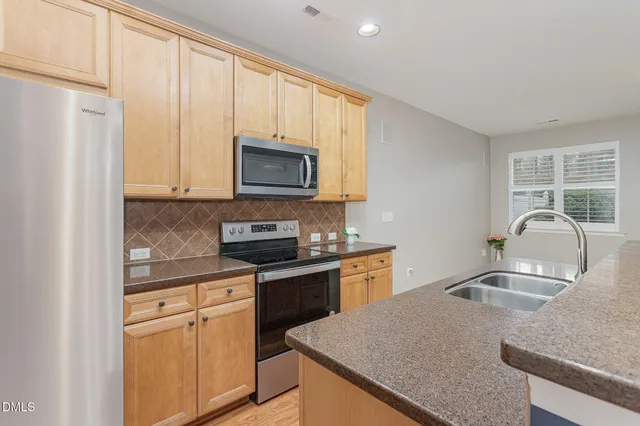 a kitchen with stainless steel appliances granite countertop a sink stove microwave and refrigerator