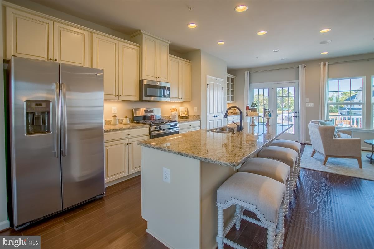 7915 Mine Run Road Hanover, MD 21076 - Photo 1 of 30 a kitchen with stainless steel appliances granite countertop a refrigerator a stove a sink a dining table and chairs with wooden floor