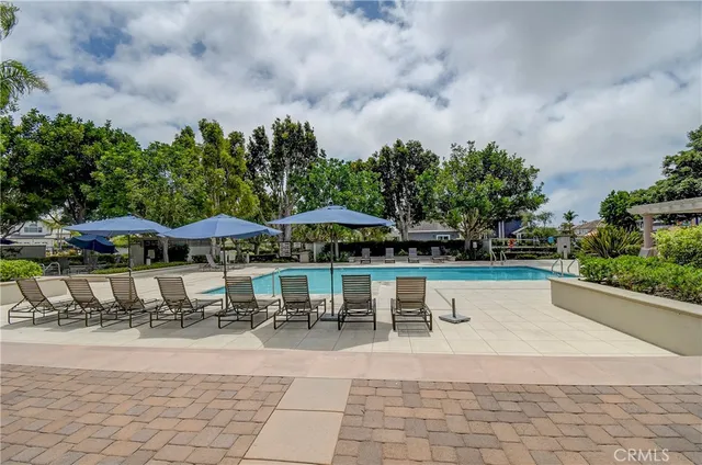 a view of a swimming pool with lawn chairs under an umbrella