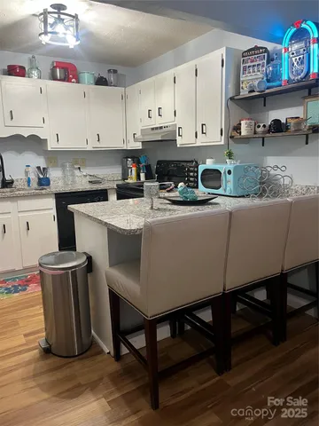a kitchen with stainless steel appliances granite countertop a table chairs sink and cabinets