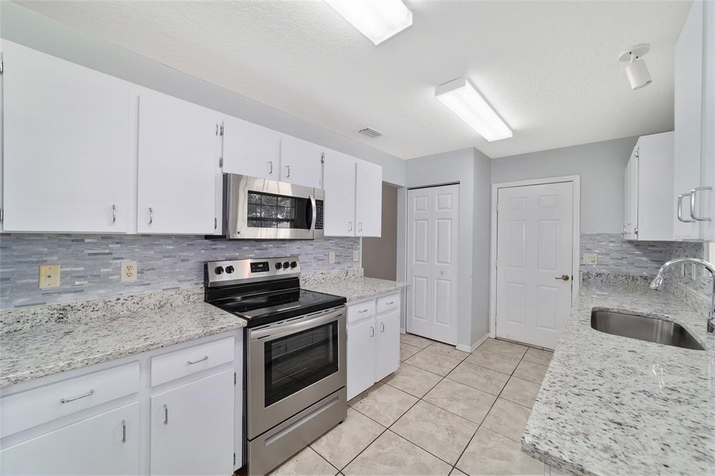 6241 Southwest 84th Place Ocala, FL 34476 - Photo 11 of 33 a kitchen with granite countertop a sink stove and microwave