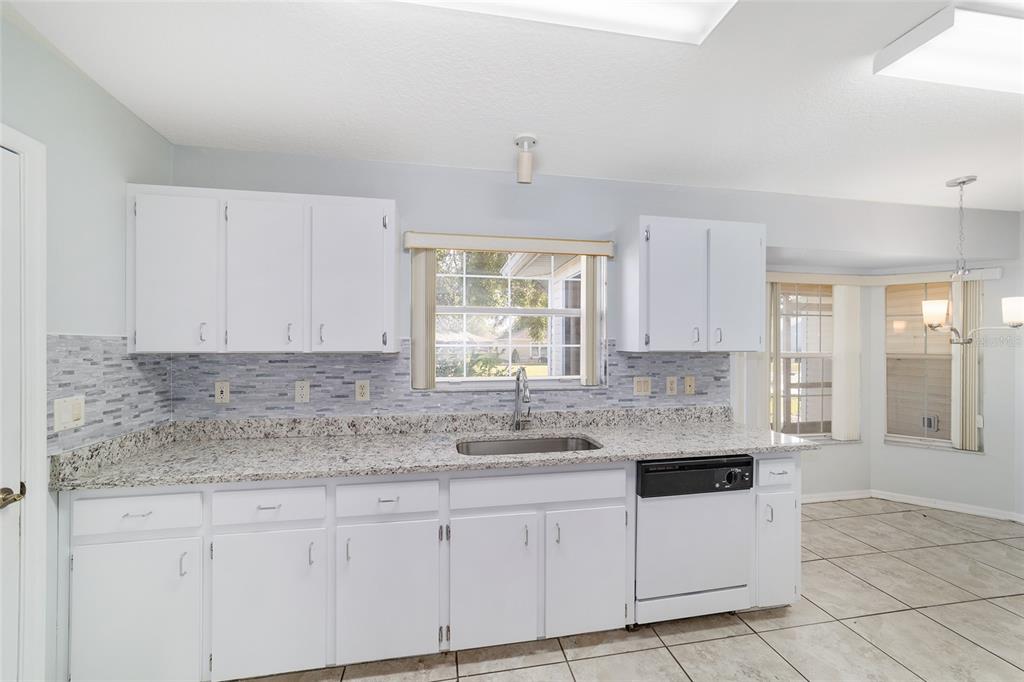 6241 Southwest 84th Place Ocala, FL 34476 - Photo 12 of 33 a kitchen with granite countertop white cabinets white appliances and a sink