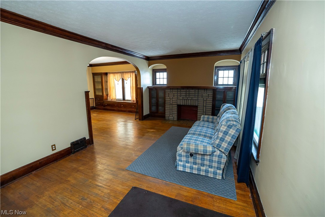 10105 Unity Avenue Cleveland, OH 44111 - Photo 15 of 35 Unfurnished living room with dark hardwood floors, ornamental molding, and a fireplace
