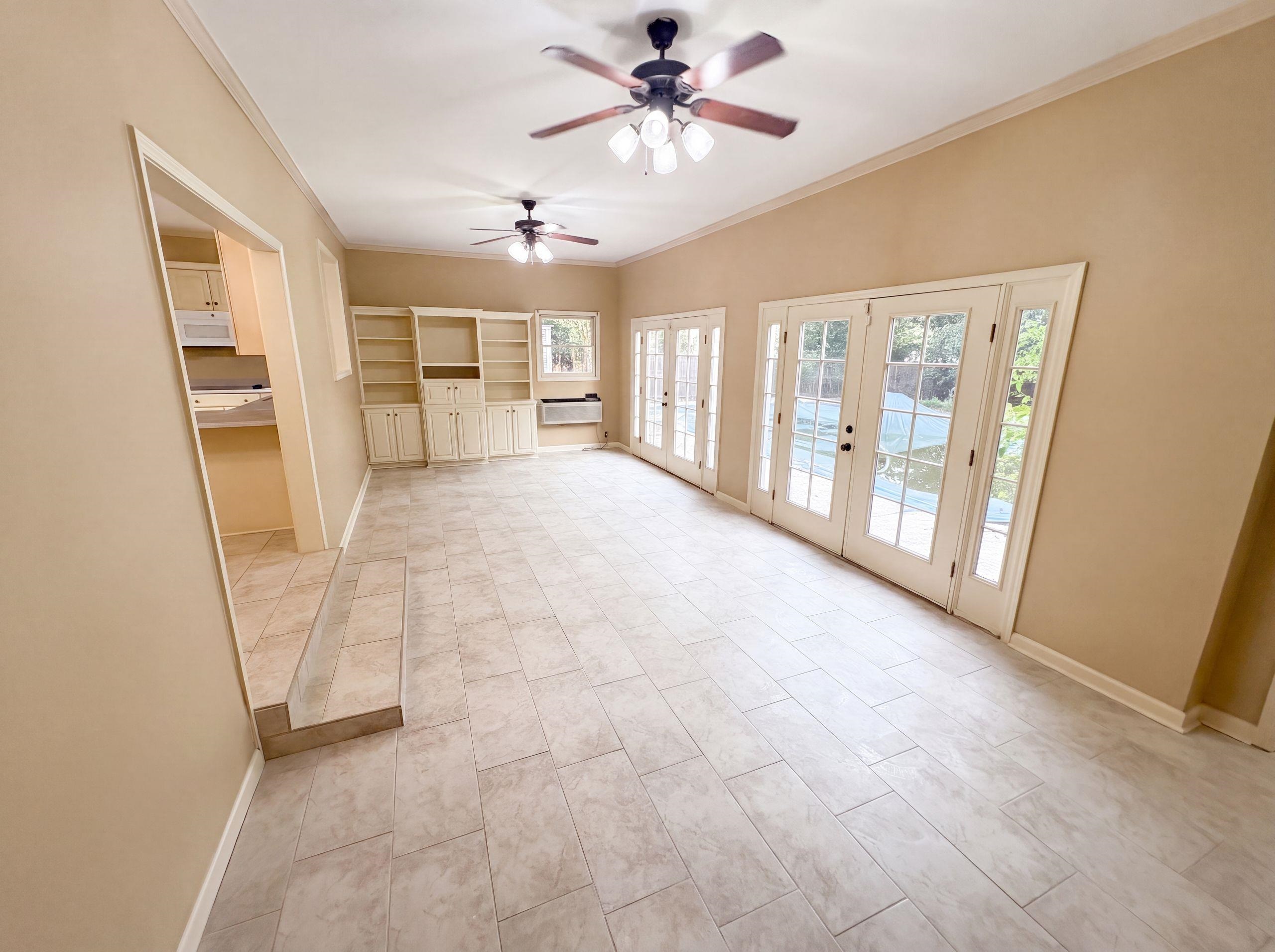 9424 Gotten Road Germantown, TN 38139 - Photo 3 of 27 Spacious living area featuring light-toned tile flooring, two ceiling fans, custom built-in cabinetry, and multiple sets of French doors with sidelights providing outdoor access