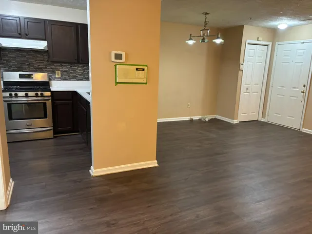 a view of kitchen with stainless steel appliances wooden floor and cabinets