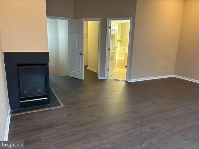 a view of an empty room with wooden floor and a fireplace