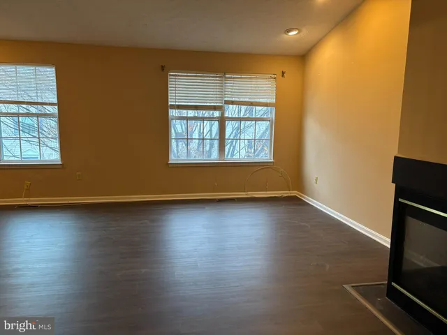an empty room with wooden floor and windows with curtains