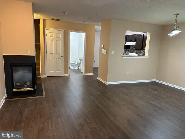 an empty room with wooden floor a fireplace and windows
