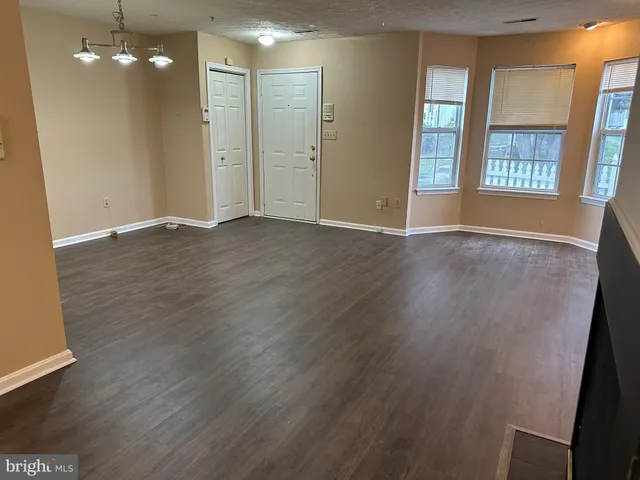 a view of an empty room with wooden floor and windows