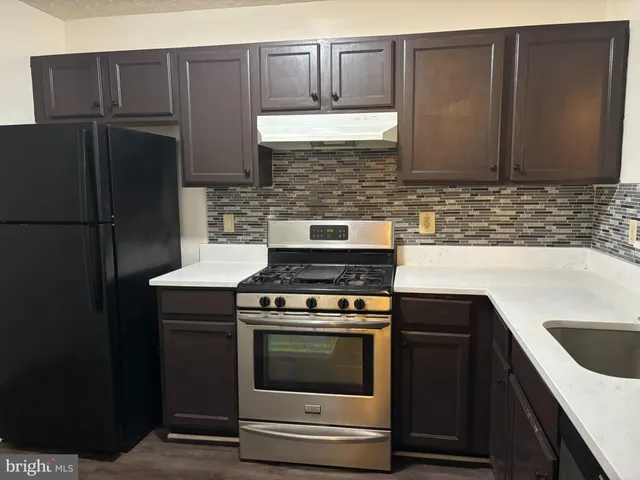 a kitchen with granite countertop a stove microwave and refrigerator