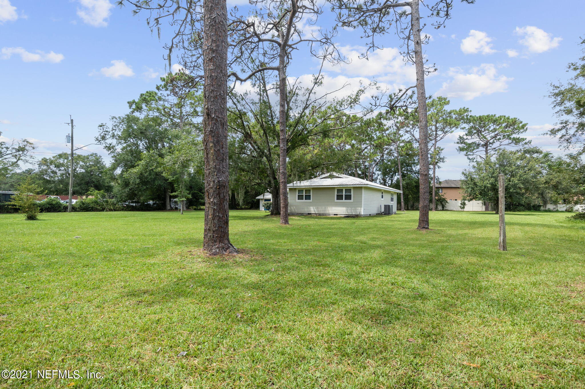 4730 Ricker Road Jacksonville, FL 32210 - Photo 2 of 30 a yellow house with a big yard and large trees