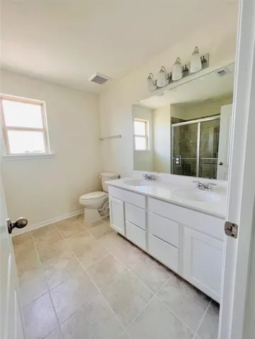 a bathroom with a double vanity sink mirror and toilet