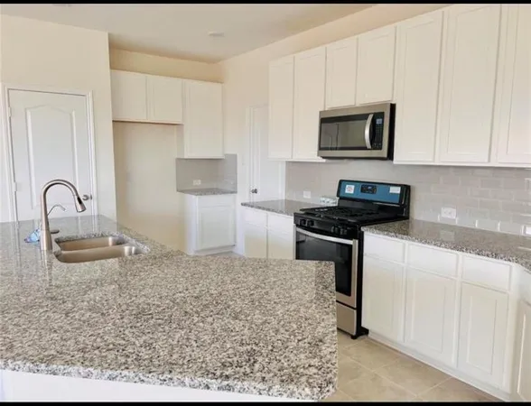 a kitchen with stainless steel appliances granite countertop a sink a stove and a microwave