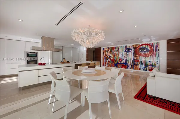 a kitchen with stainless steel appliances kitchen island granite countertop a dining table chairs and white cabinets