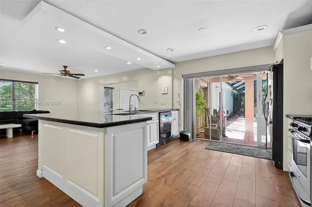 a kitchen with stainless steel appliances granite countertop a refrigerator a sink dishwasher a oven and a dining table with wooden floor