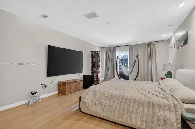 a bedroom with a bed and a flat tv screen on dresser