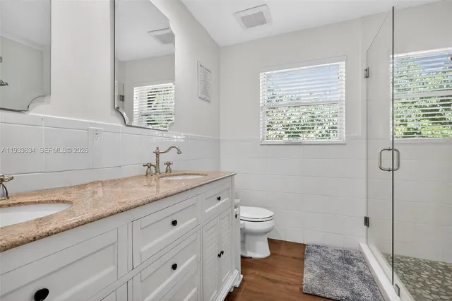 a bathroom with a granite countertop sink a toilet and a mirror
