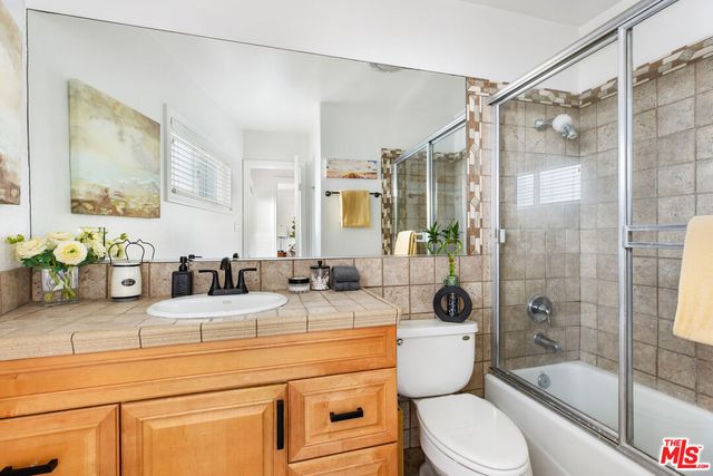 a bathroom with a granite countertop sink a toilet a mirror a bathtub and shower