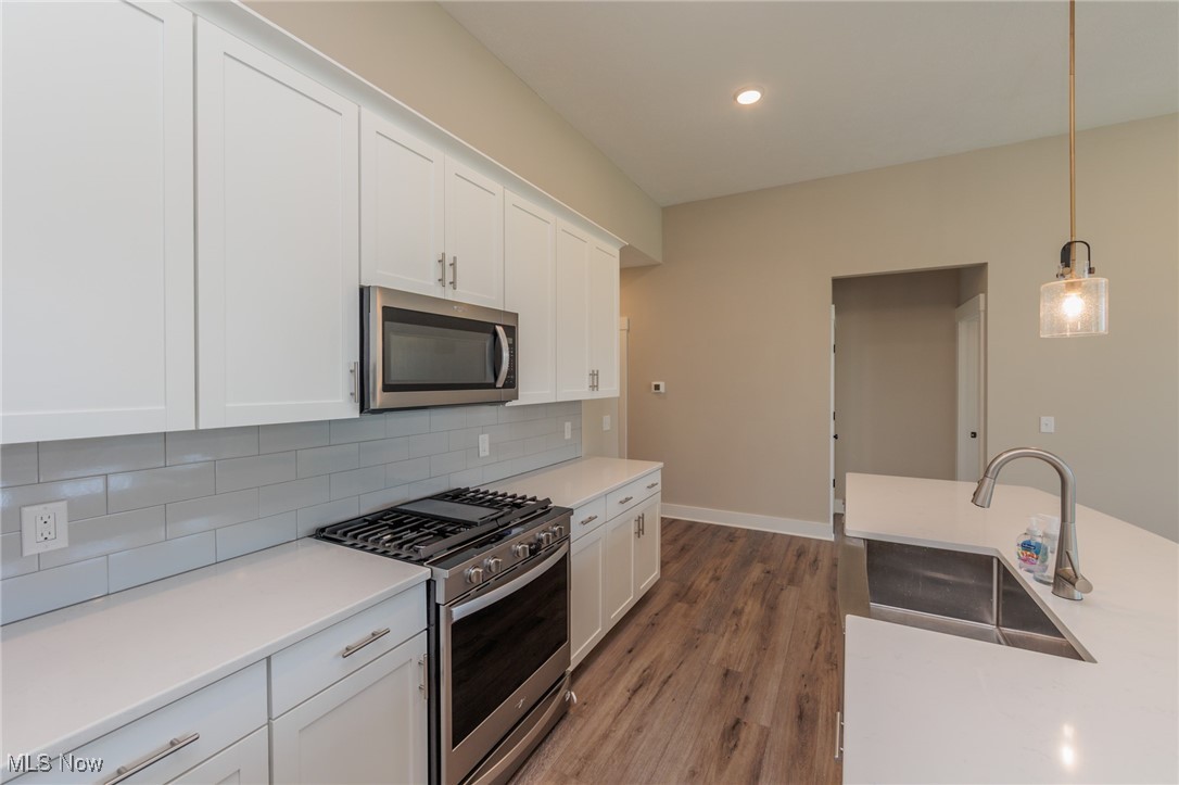 36458 Appian Way North Ridgeville, OH 44039 - Photo 10 of 37 Kitchen with decorative light fixtures, wood-type flooring, stainless steel appliances, sink, and white cabinetry