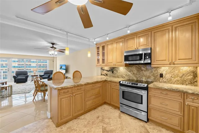 a kitchen with stainless steel appliances kitchen island granite countertop a refrigerator and a sink