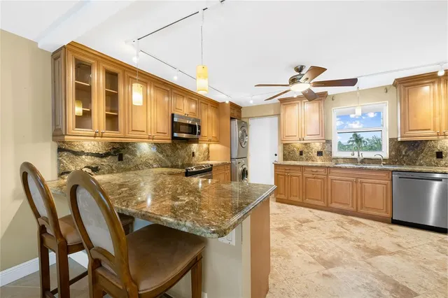 a large kitchen with stainless steel appliances kitchen island granite countertop a sink and a refrigerator