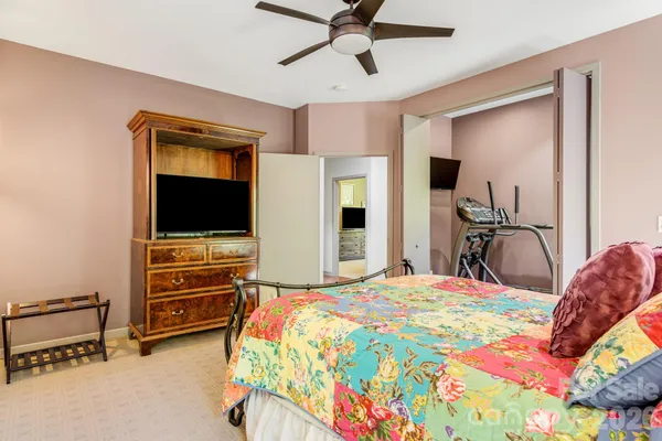 a bedroom with a bed and a flat tv screen on dresser