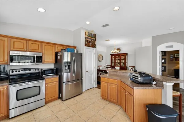 a kitchen with stainless steel appliances kitchen island granite countertop a table chairs and a refrigerator