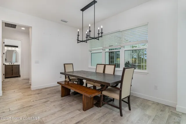 a dining room with wooden floor a chandelier a wooden table and chairs