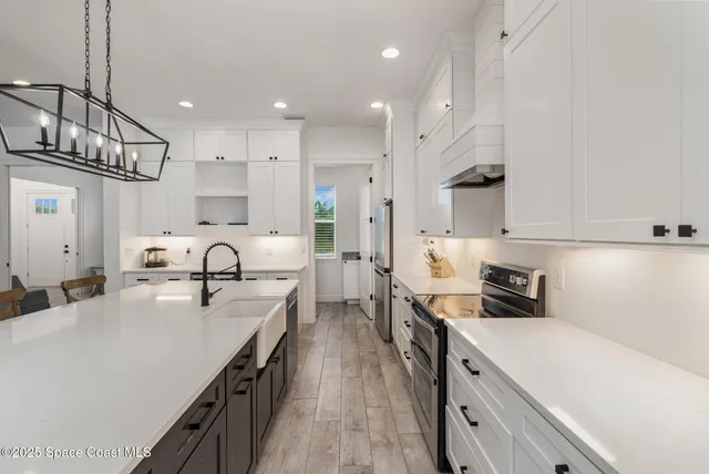 a large kitchen with stainless steel appliances lots of counter space sink refrigerator and cabinets
