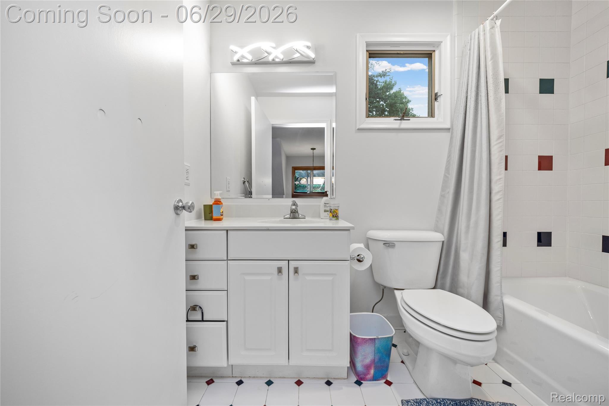 6085 Worlington Road Bloomfield Hills, MI 48301 - Photo 54 of 75 Bathroom featuring a white vanity with integrated sink, overhead vanity lighting, a window, white tile surround bathtub, and a tiled floor with accent squares