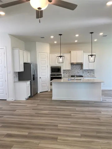 a view of kitchen with kitchen island stainless steel appliances refrigerator stove microwave and cabinets