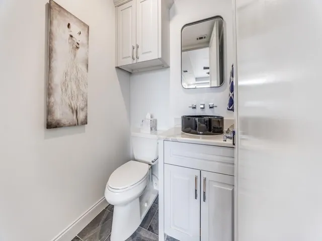 a bathroom with a toilet sink vanity and mirror