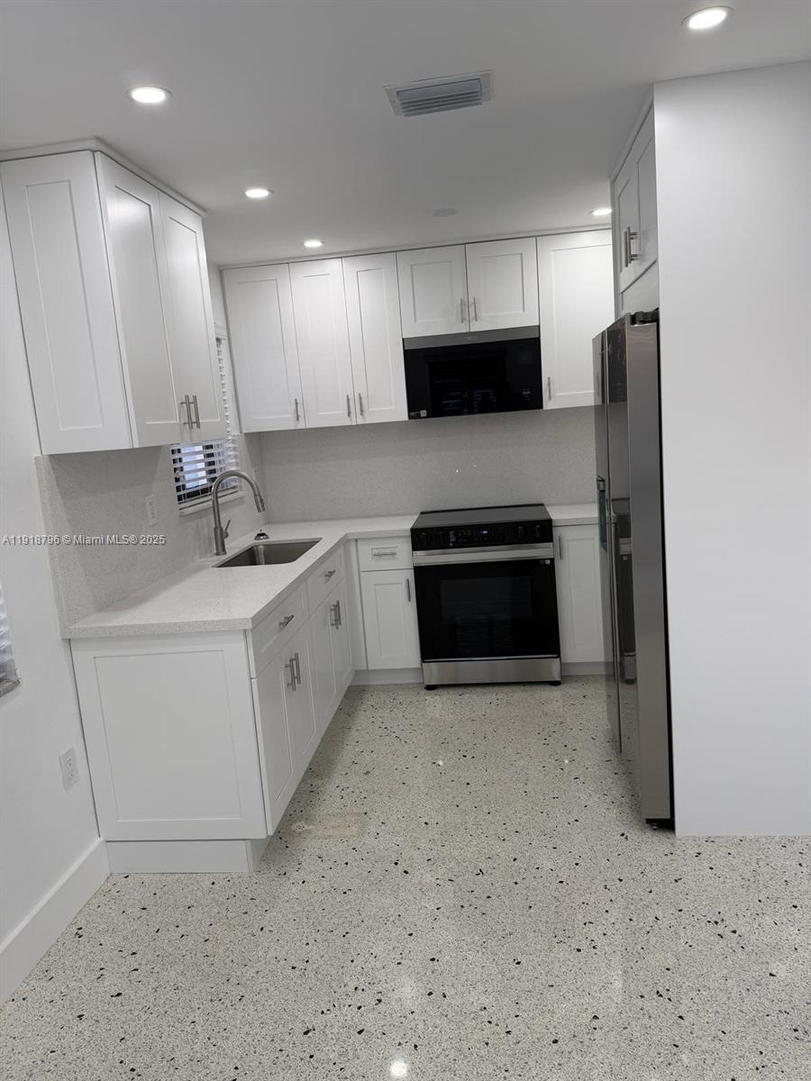 5133 Northwest 4th Street, Unit 1 Miami, FL 33126 - Photo 2 of 11 a kitchen with stainless steel appliances a refrigerator sink and microwave
