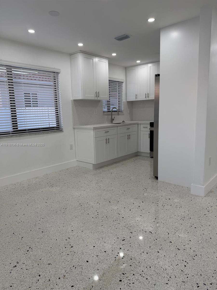5133 Northwest 4th Street, Unit 1 Miami, FL 33126 - Photo 5 of 11 a large white kitchen with kitchen island a sink a stove a refrigerator and white cabinets