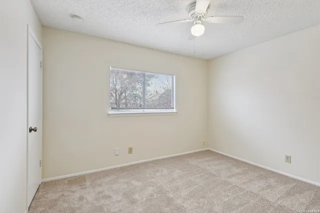 an empty room with a fan & a window