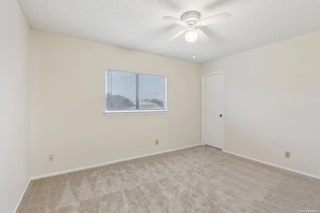 an empty room with a chandelier fan and windows