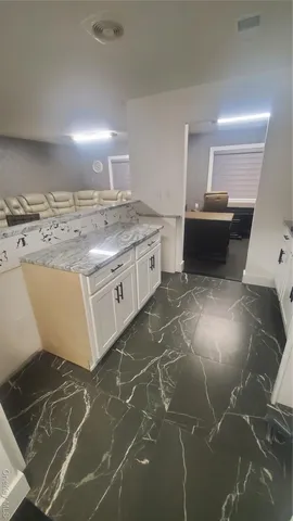a kitchen with kitchen island granite countertop a sink and a stove