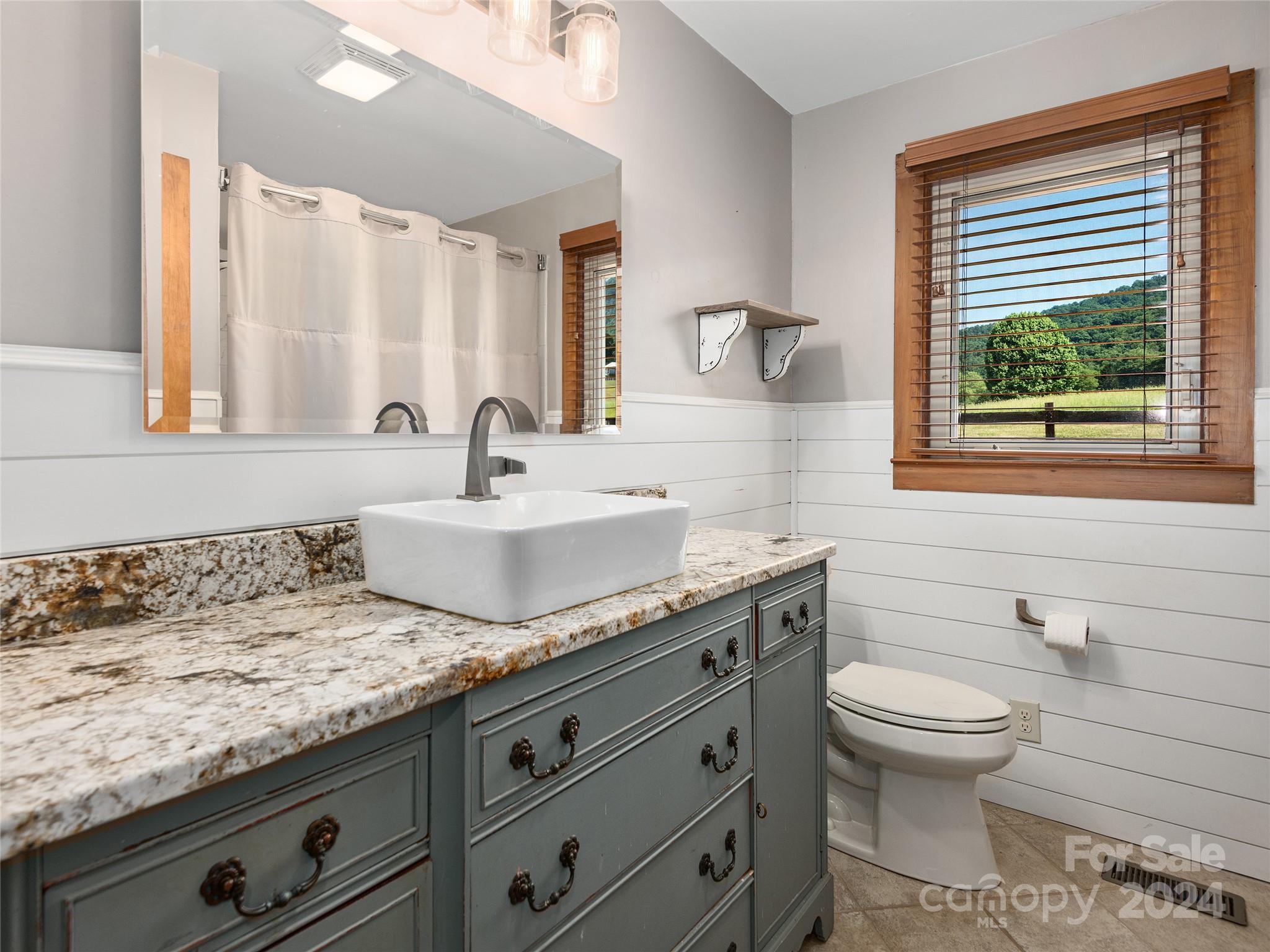 2356 Panther Creek Road Clyde, NC 28721 - Photo 17 of 22 a bathroom with a granite countertop toilet sink and mirror