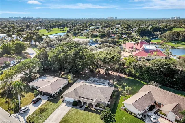 a view of a white house with a big yard plants and large trees