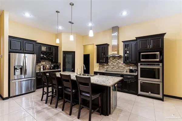a kitchen with stainless steel appliances kitchen island granite countertop a refrigerator a stove a sink and chairs